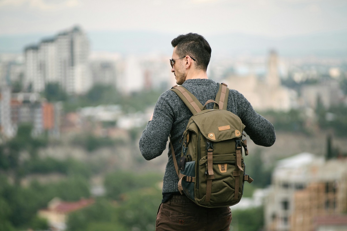 man with a backpack looking out over a city