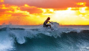surfer riding a wave during a vibrant sunset
